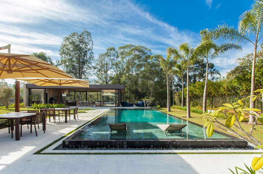 Totalmente integrada à natureza, esta piscina conta com uma “prainha”, ou seja, uma área rasa na qual as espreguiçadeiras ficam dispostas. O recurso amplia a segurança no uso para crianças e idosos | Projeto: Korman Arquitetos | Foto: Eduardo Pozella